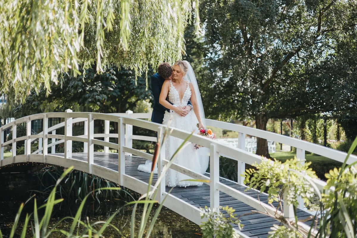 Couple cuddling on the bridge whilst looking at the pond at High House