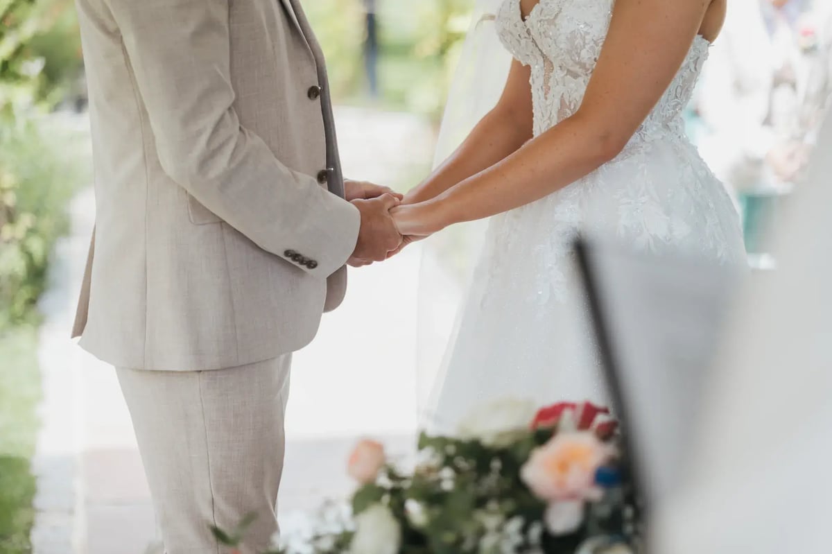 Close up of couple holding hands under Gazebo outside at High House