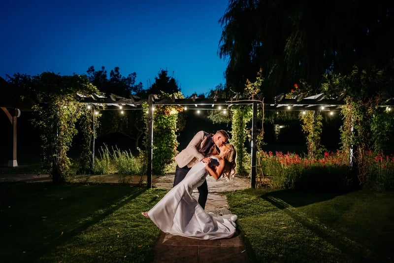 Groom dipping bride and kissing for a photo outside at High House