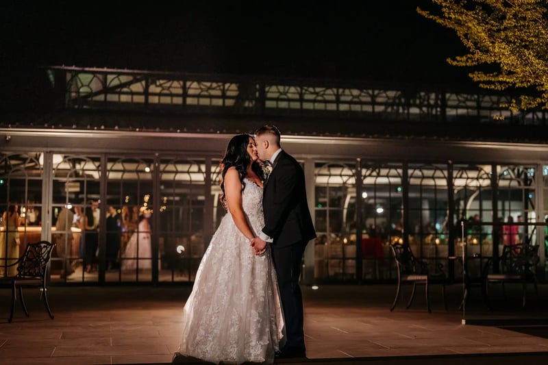 Bride and groom kissing in the evening outside the Orangery at High House