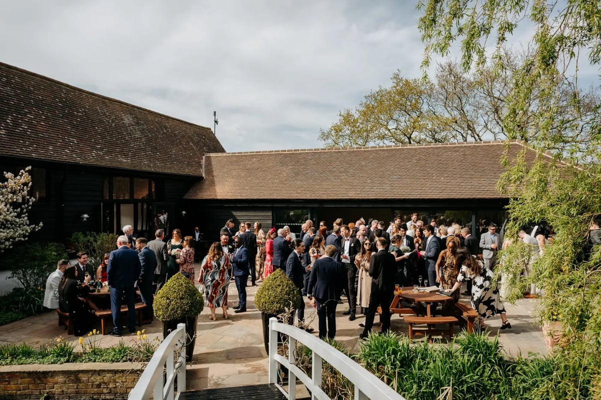 Guests waiting and talking outside wedding barn at High House