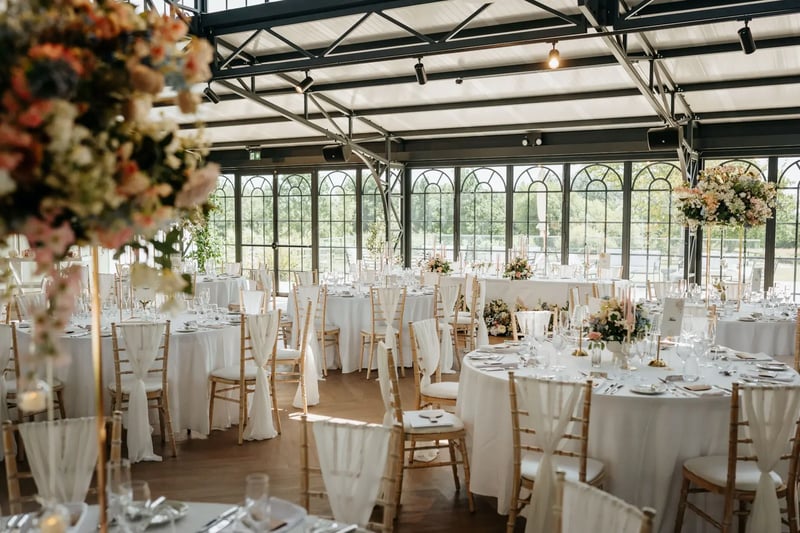 Circle tables dressed for a wedding with colourful flowers in the Orangery at High House