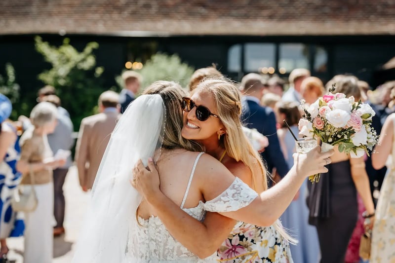 Bride hugging smiling guest at High House