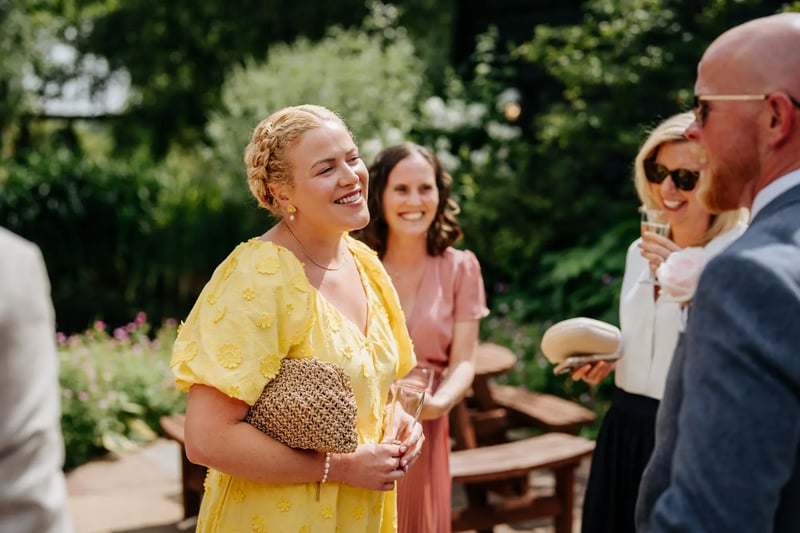 Wedding guest stood in group talking outside at High House
