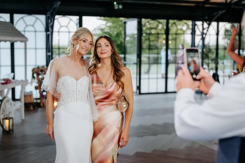 Bride and guest posing for a photo in the Orangery at High House