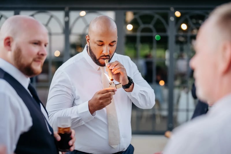 Wedding guest smoking a cigar outside the Orangery at High House