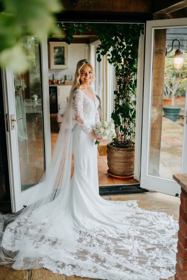 Bride posing with bouquet of flowers outside dressing room at High House