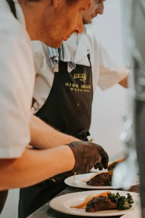 chefs preparing meal plates to serve at high house